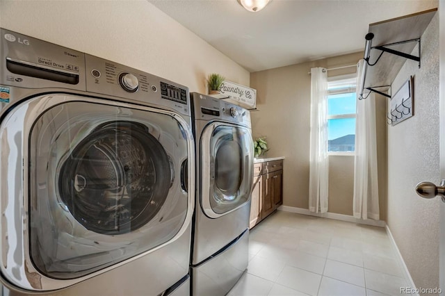 clothes washing area featuring washer and dryer, cabinet space, baseboards, and light tile patterned flooring