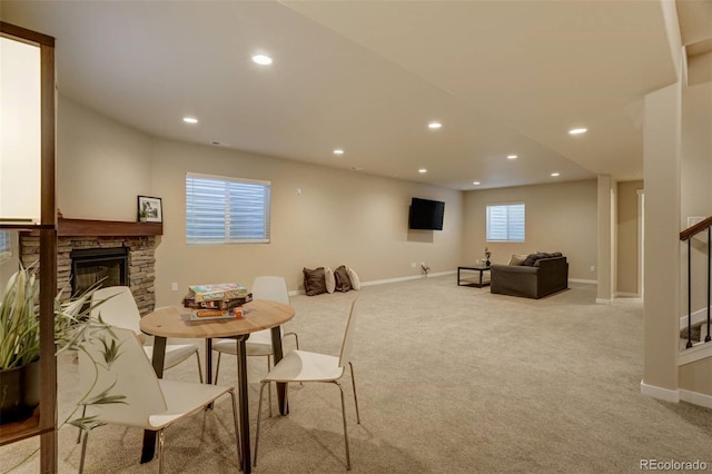 carpeted living room with a stone fireplace