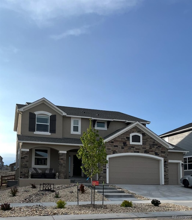 view of front of property with an attached garage, covered porch, stone siding, driveway, and stucco siding