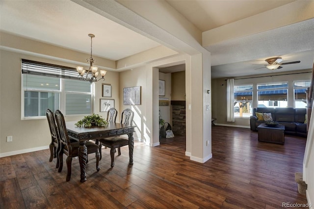 dining room featuring ceiling fan with notable chandelier, dark wood-style flooring, and baseboards