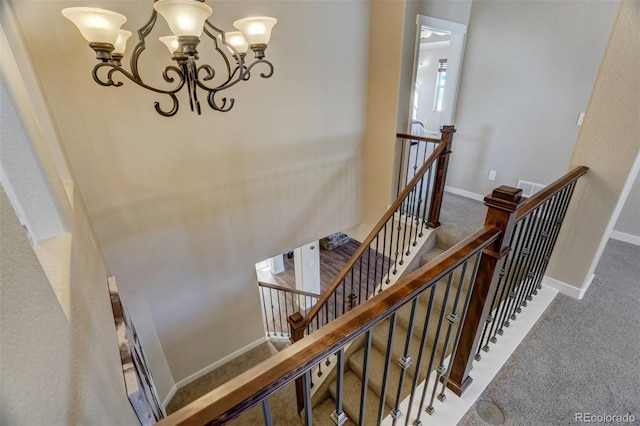 stairs featuring baseboards, a chandelier, and carpet flooring