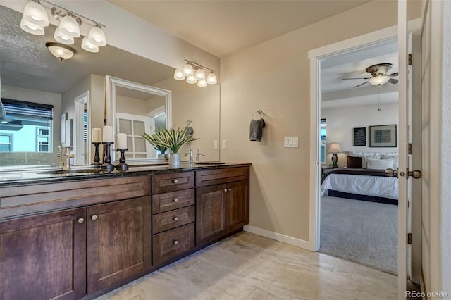 ensuite bathroom featuring double vanity, ensuite bath, baseboards, and a sink