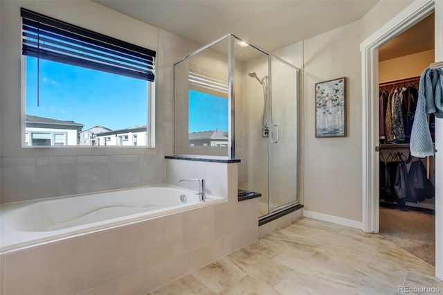 bathroom featuring a spacious closet, a shower stall, and a bath