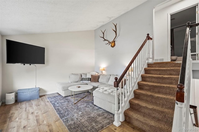 living room with a textured ceiling, wood finished floors, stairs, lofted ceiling, and visible vents