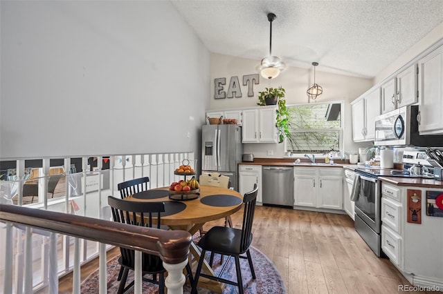 kitchen with dark countertops, vaulted ceiling, a textured ceiling, and stainless steel appliances