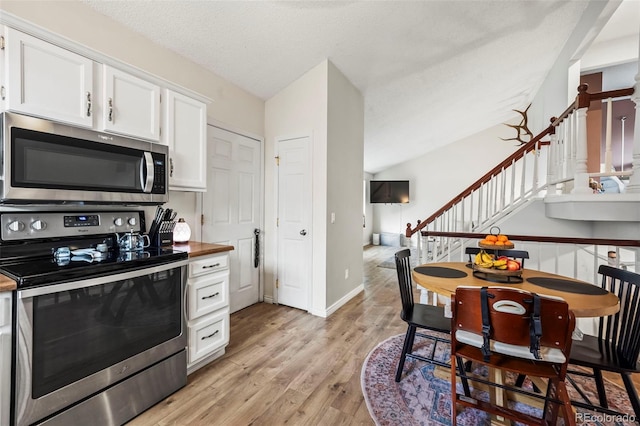 kitchen featuring baseboards, white cabinetry, stainless steel appliances, and light wood-style floors