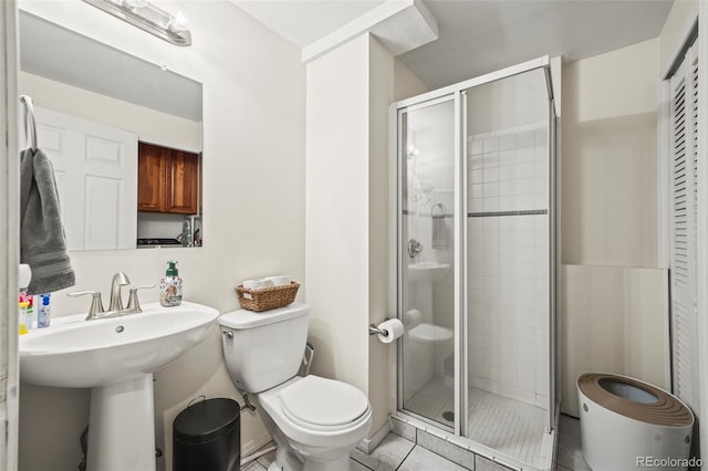 bathroom featuring a stall shower, tile patterned floors, a sink, and toilet