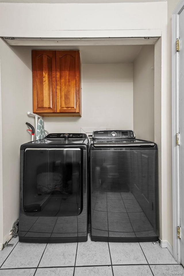 washroom featuring washing machine and dryer, baseboards, light tile patterned flooring, and cabinet space