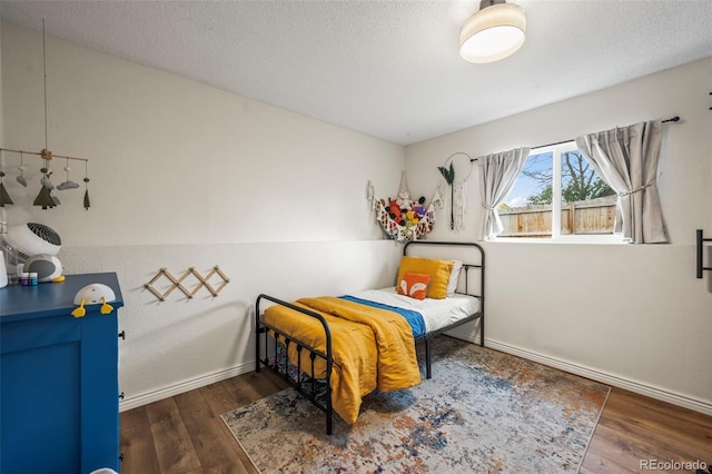 bedroom featuring wood finished floors, a textured ceiling, and baseboards