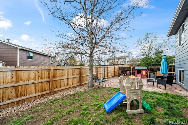 view of yard featuring a fenced backyard, a patio area, and a playground