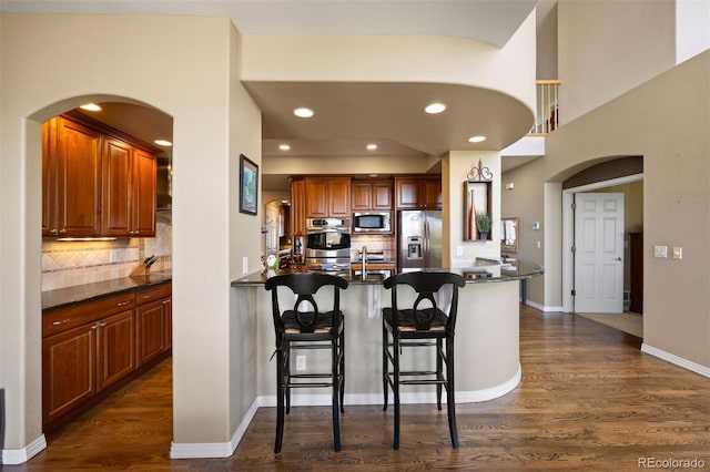 4373 E Phillips Pl, Centennial, CO 80122 - kitchen featuring arched walkways, stainless steel appliances, a peninsula, and dark wood-style floors
