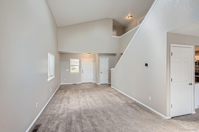 entrance foyer featuring high vaulted ceiling, light carpet, stairs, and baseboards