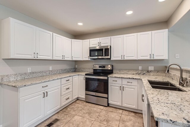 kitchen featuring appliances with stainless steel finishes, a sink, recessed lighting, white cabinetry, and light tile patterned floors