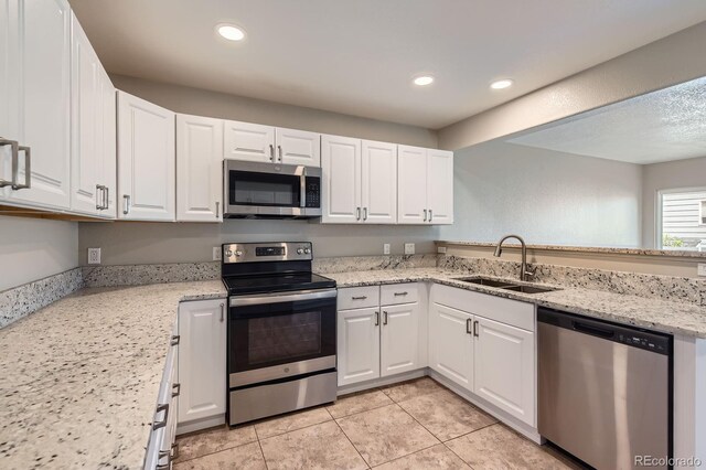 kitchen with appliances with stainless steel finishes, a sink, white cabinets, light tile patterned floors, and recessed lighting