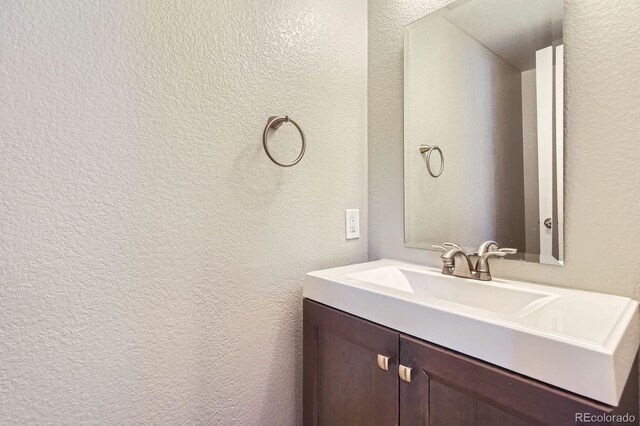 bathroom with a textured wall and vanity