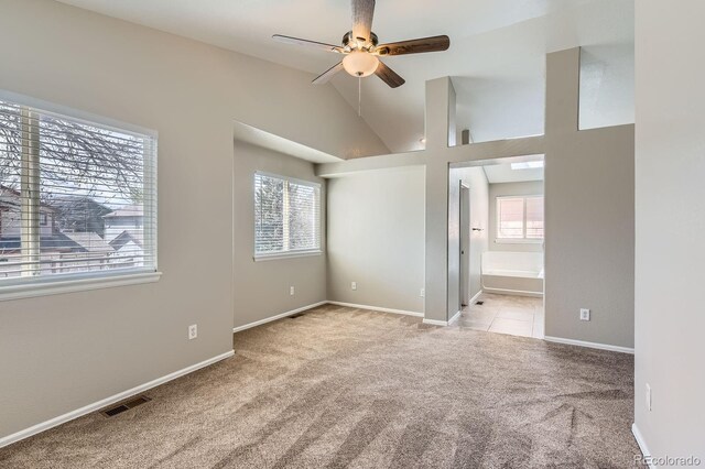 carpeted spare room featuring plenty of natural light, ceiling fan, baseboards, and high vaulted ceiling