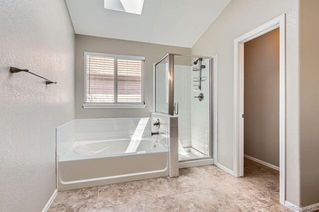 bathroom featuring a skylight, a shower stall, a bath, a textured wall, and baseboards