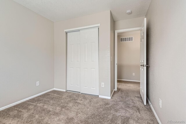 unfurnished bedroom with carpet, a closet, and baseboards