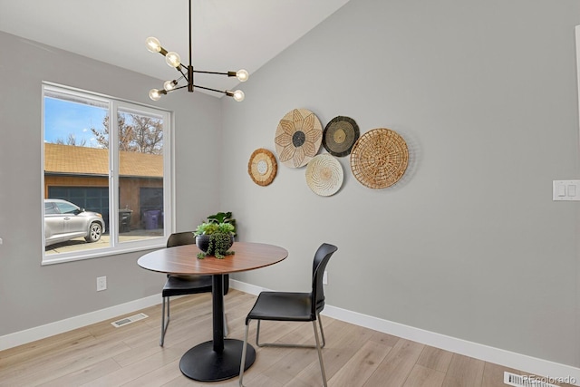 dining area with vaulted ceiling, a chandelier, and light hardwood / wood-style flooring