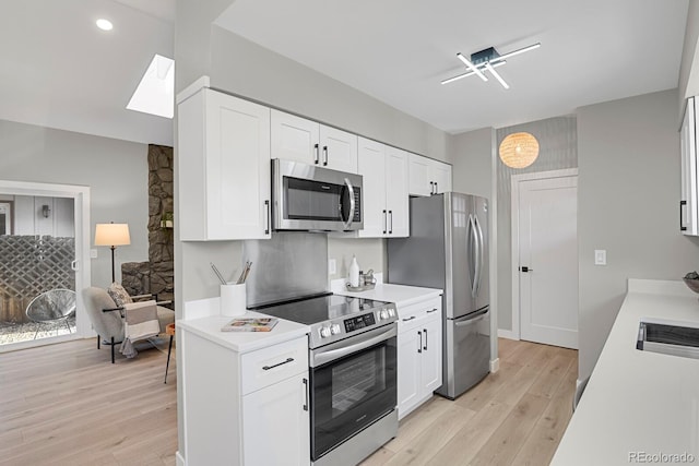 kitchen with light hardwood / wood-style flooring, white cabinets, and appliances with stainless steel finishes