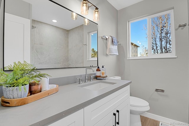 bathroom with plenty of natural light, vanity, toilet, and baseboards