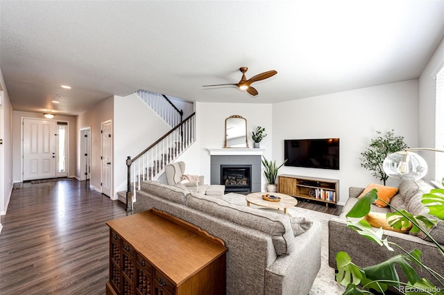 living room featuring dark hardwood / wood-style floors, ceiling fan, and a tile fireplace