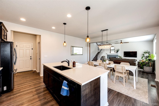 kitchen featuring a center island with sink, dark hardwood / wood-style floors, sink, and fridge