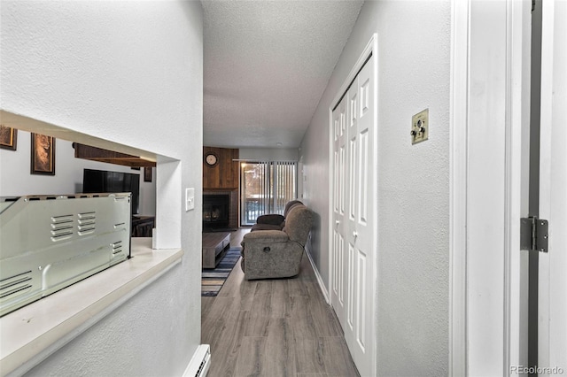 hallway with light hardwood / wood-style flooring and a textured ceiling