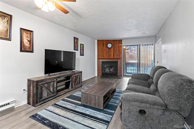 living room with wood-type flooring, a baseboard heating unit, ceiling fan, and a textured ceiling