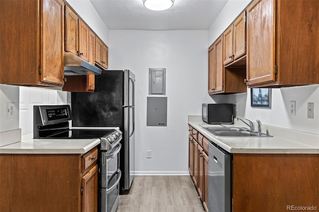 kitchen featuring appliances with stainless steel finishes, sink, electric panel, and light hardwood / wood-style flooring