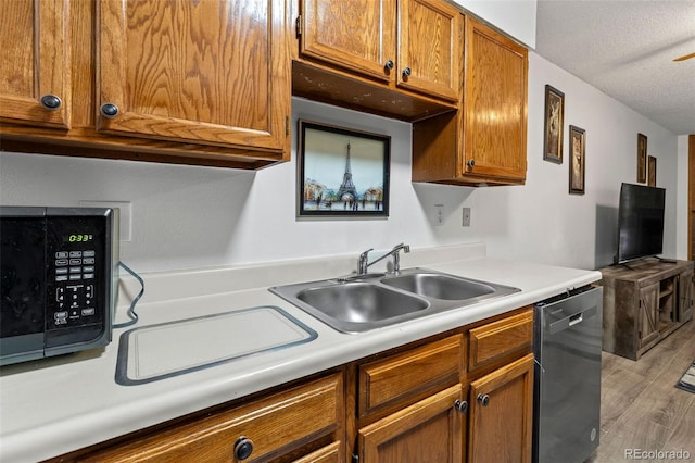 kitchen with hardwood / wood-style flooring, dishwasher, sink, and a textured ceiling