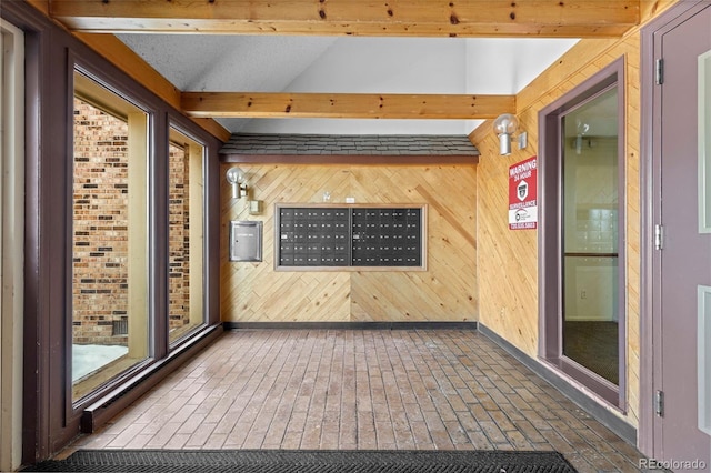 interior space with vaulted ceiling with beams, a mail area, and wood walls