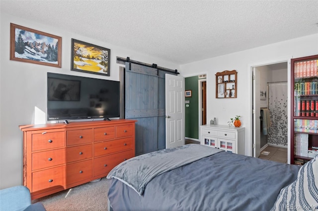 bedroom with a textured ceiling, ensuite bath, and a barn door