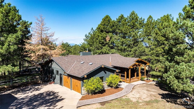 view of front of house featuring concrete driveway, a shingled roof, and a chimney