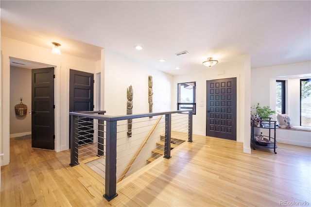 foyer entrance with a healthy amount of sunlight, light wood-style floors, baseboards, and visible vents