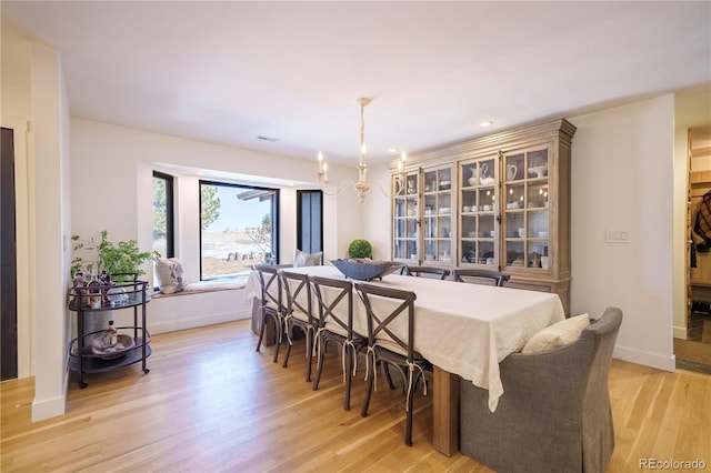 dining space featuring a chandelier, light wood-type flooring, and baseboards