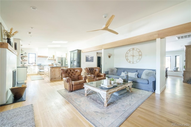 living room featuring light wood-type flooring, visible vents, and a ceiling fan