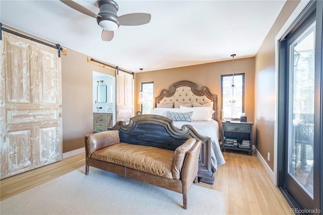 bedroom with a barn door, multiple windows, and light wood-style floors