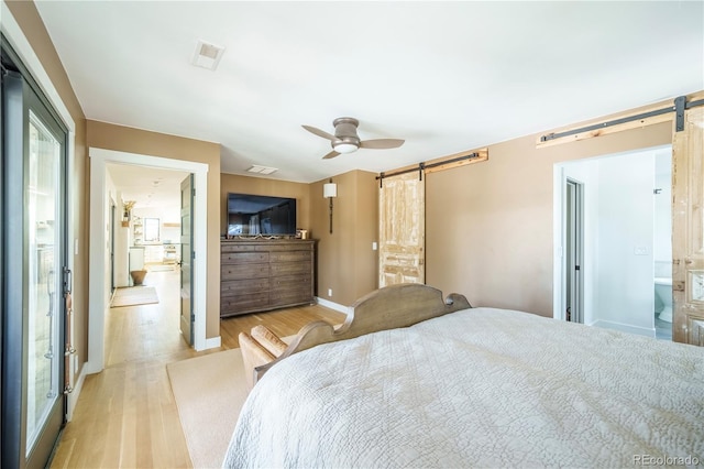 bedroom featuring a ceiling fan, light wood-type flooring, baseboards, and a barn door