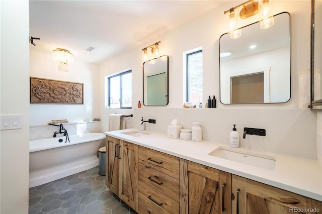 bathroom with double vanity, a soaking tub, a sink, and visible vents