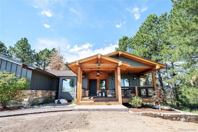 view of front of house featuring a porch, stone siding, and board and batten siding