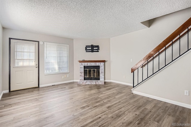 unfurnished living room with a fireplace, light wood-type flooring, and a textured ceiling