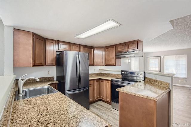 kitchen with kitchen peninsula, light stone countertops, light hardwood / wood-style flooring, stainless steel appliances, and sink