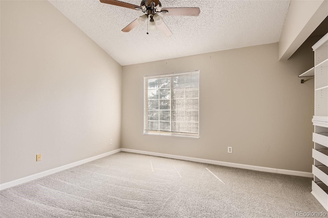 carpeted empty room featuring vaulted ceiling, a textured ceiling, and ceiling fan