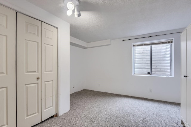 unfurnished bedroom with a textured ceiling, a closet, and carpet