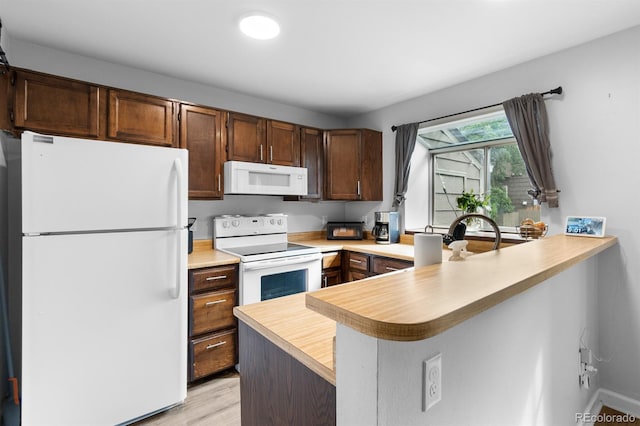 9632 W Chatfield Ave Unit C, Littleton, CO 80128 - kitchen with white appliances, light countertops, a peninsula, light wood-style floors, and dark brown cabinets