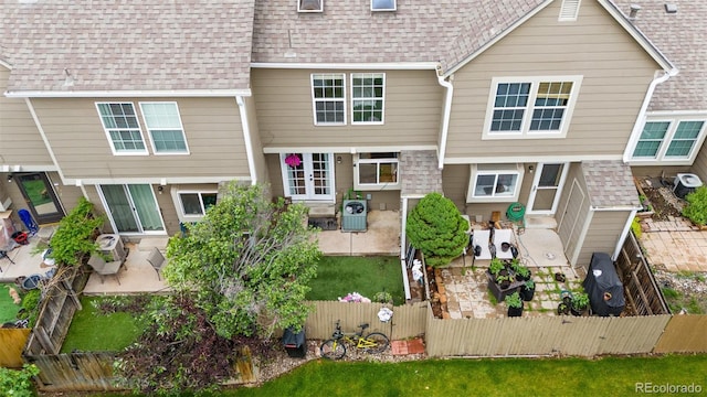9632 W Chatfield Ave Unit C, Littleton, CO 80128 - rear view of house featuring a patio, a fenced front yard, and roof with shingles