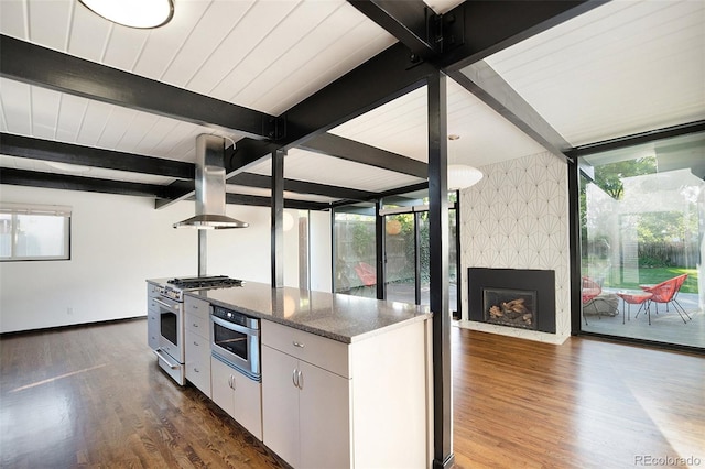 kitchen featuring appliances with stainless steel finishes, dark hardwood / wood-style flooring, dark stone counters, island range hood, and white cabinetry