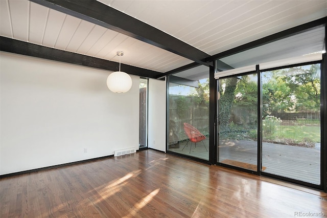 spare room with expansive windows, beam ceiling, and wood-type flooring