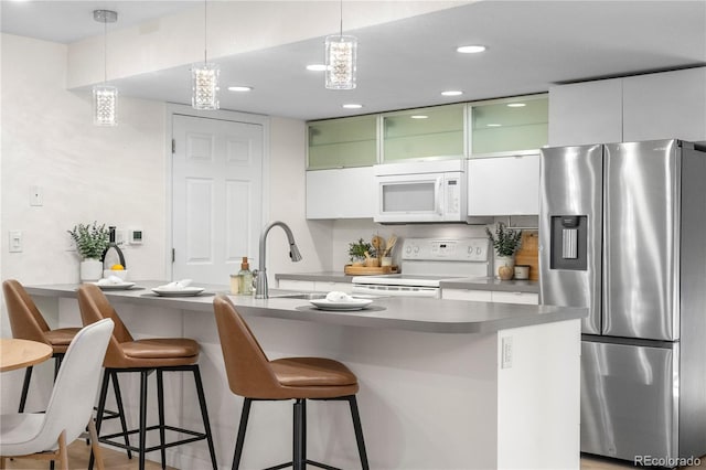 9587 W 89th Cir, Broomfield, CO 80021 - kitchen featuring white appliances, a kitchen bar, white cabinets, recessed lighting, and hanging light fixtures